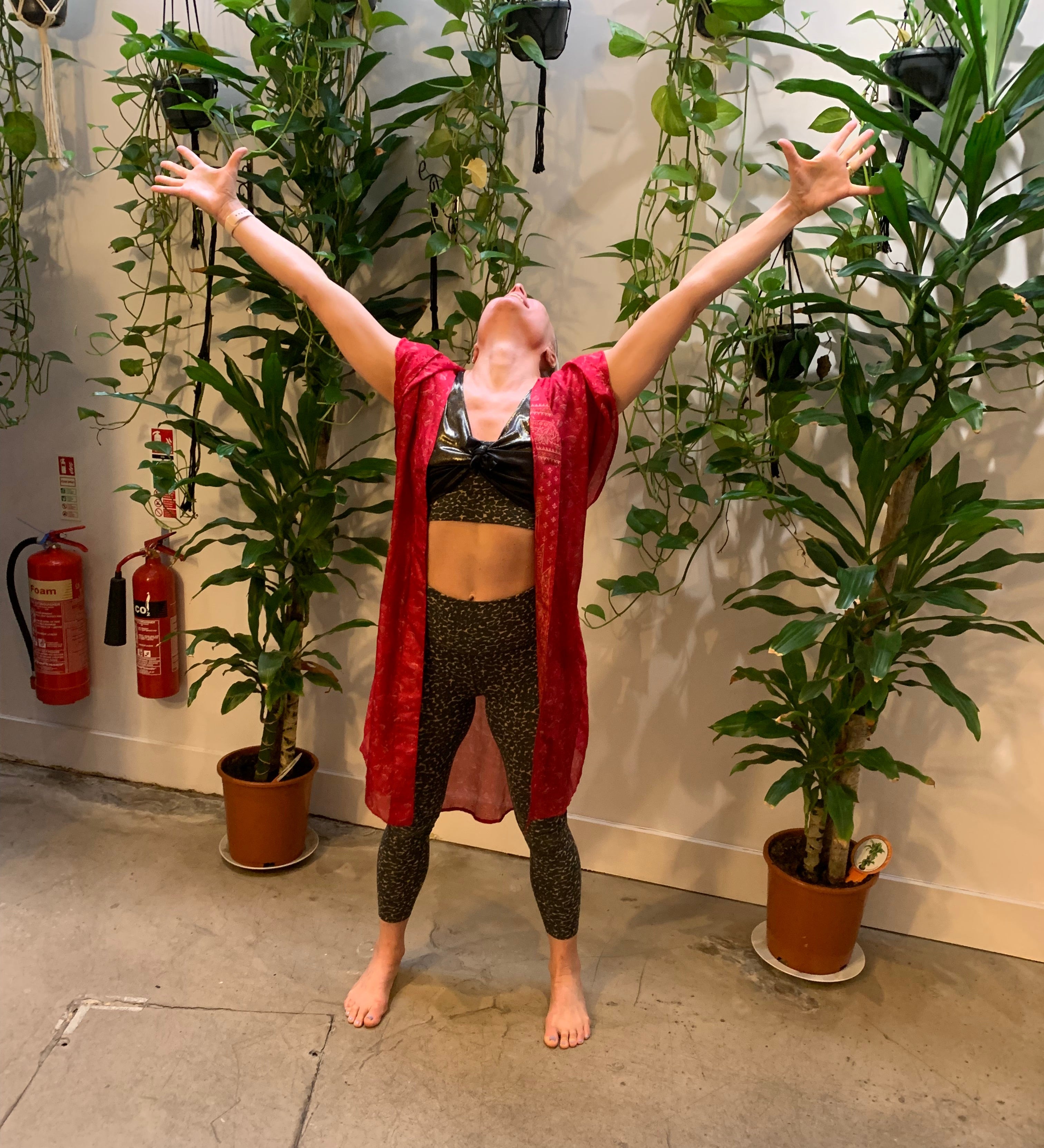 Rebecca standing in a yoga studio with arms in the air