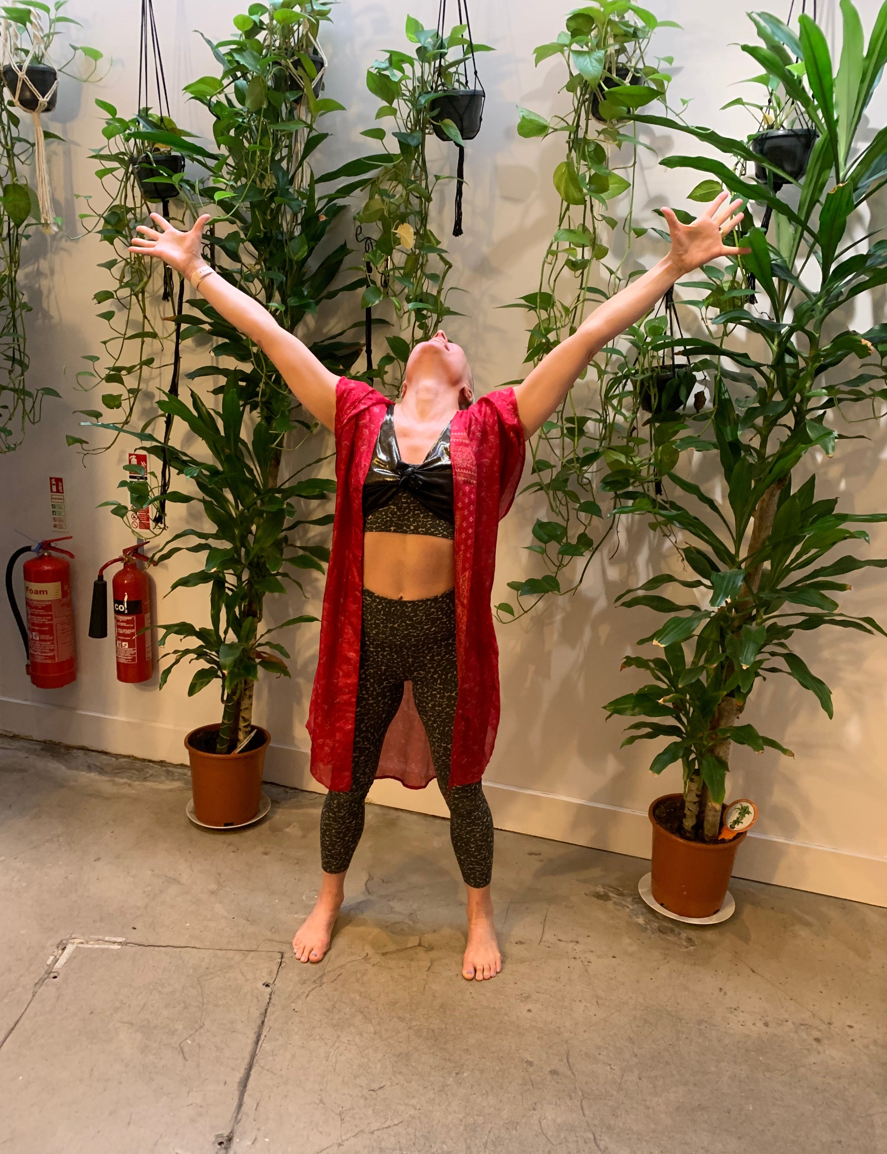 Rebecca standing in a yoga studio with arms in the air