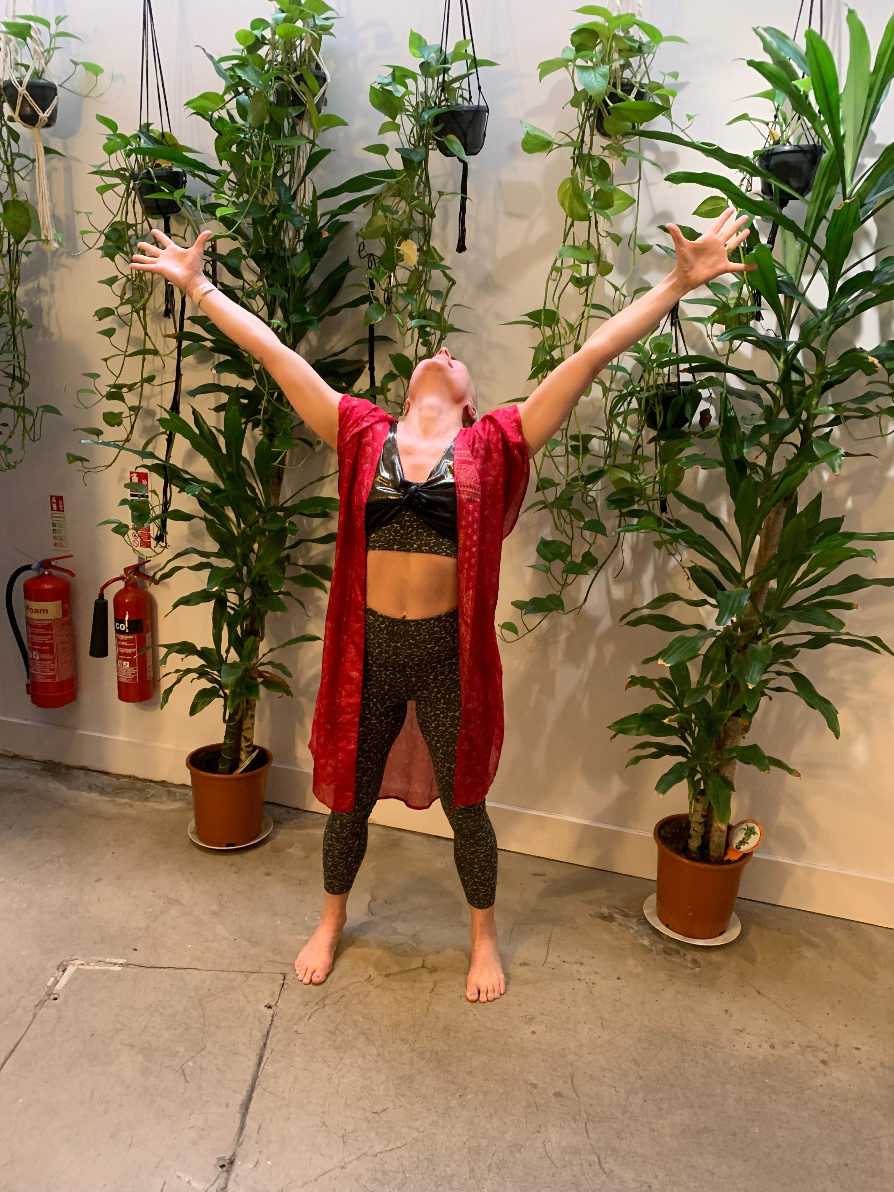 Rebecca standing in a yoga studio with arms in the air