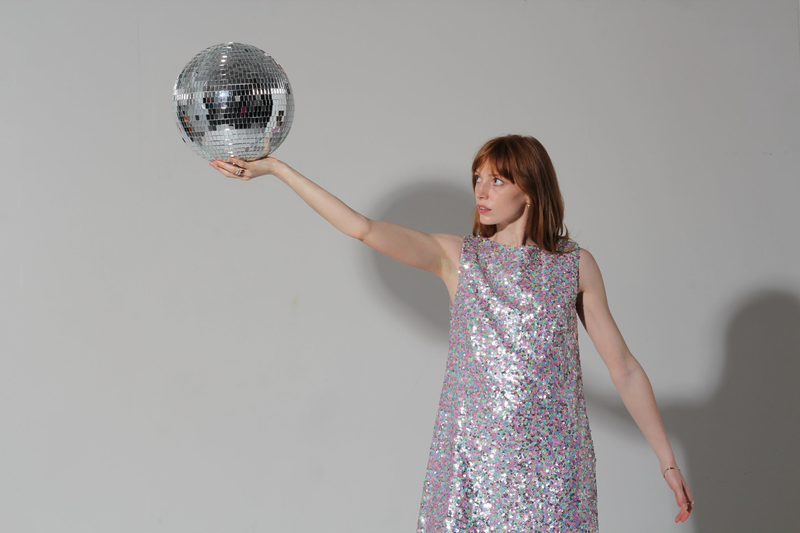 woman holding glitter ball wearing imu shift dress in pearl sequins